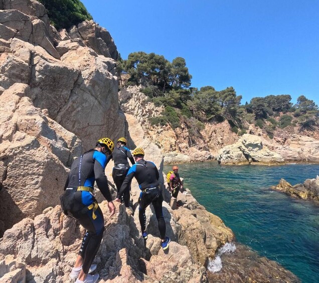 A group of people climbing a rocky cliff by a body of water. 3