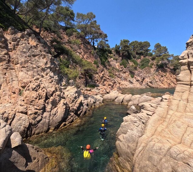 A group of people kayaking in a narrow, rocky waterway surrounded by cliffs and trees. 2