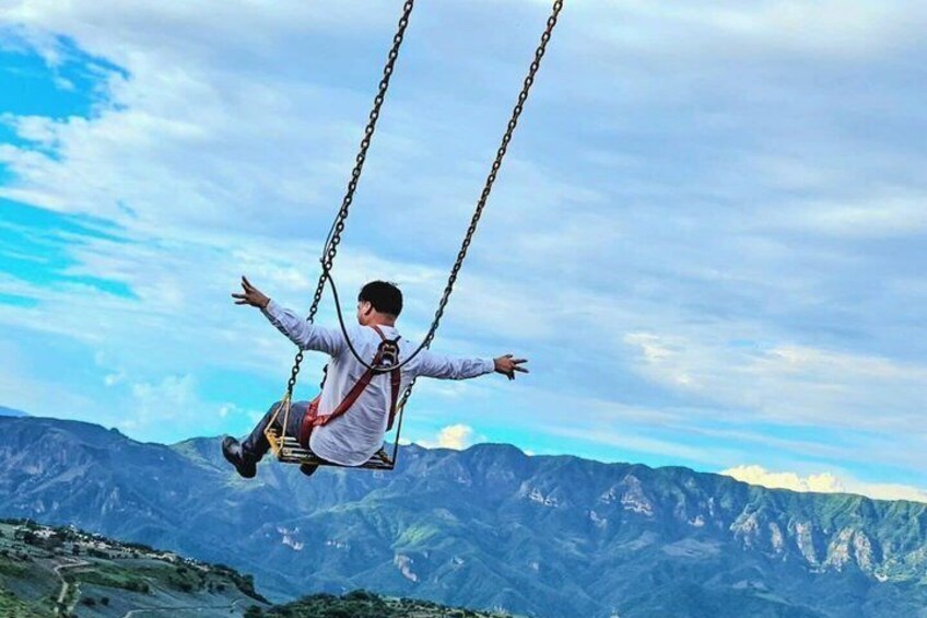 A person on a swing with a mountainous landscape in the background. 2