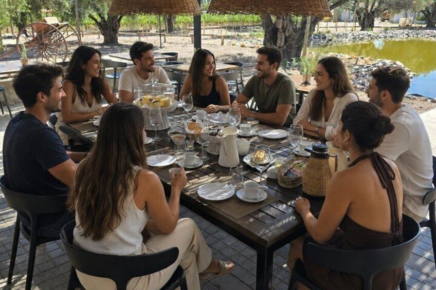 A group of people dining outdoors at a table with various dishes and drinks. 1