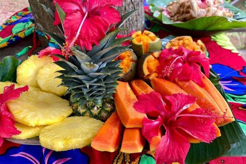 A tropical fruit display with pineapples, papayas, and a hibiscus flower. 3