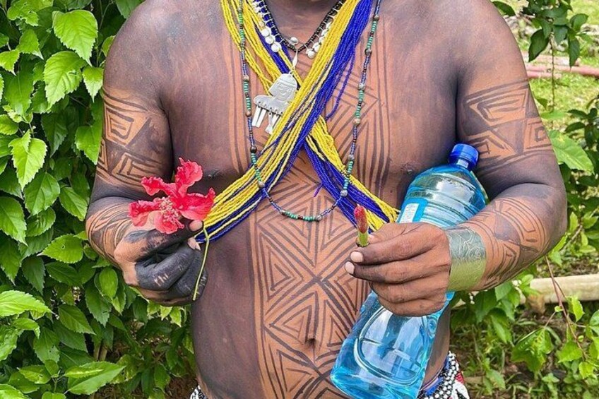 A person with tattoos, holding a red flower and a blue water bottle. 4
