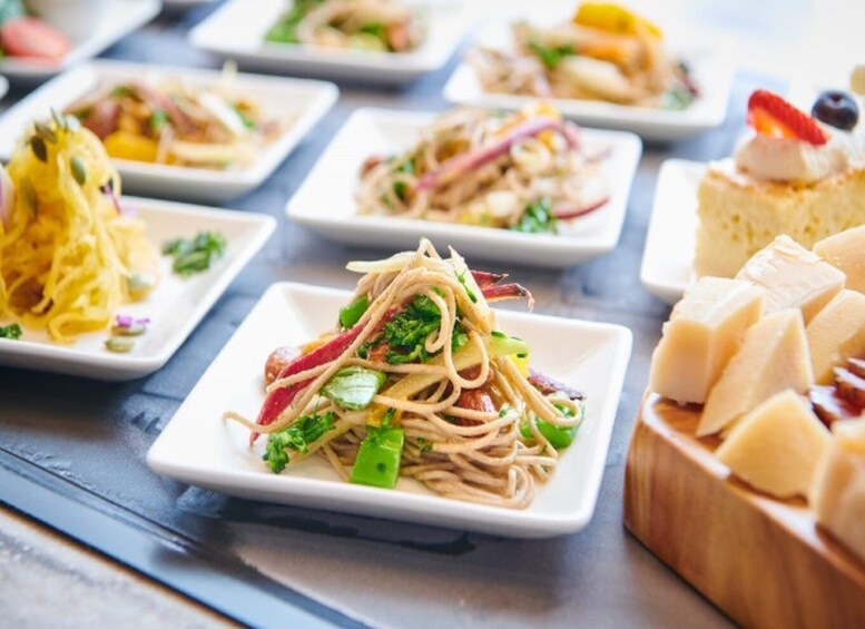 A variety of dishes on square plates, including noodles with vegetables and a dessert with fruit. 3