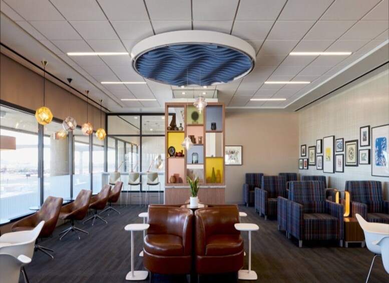 A modern waiting area with leather chairs, a central plant, and a wall decorated with framed pictures. 2