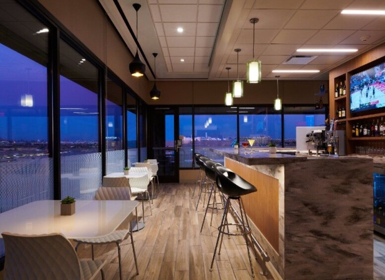 A modern bar with a city view, wooden flooring, and bar stools. 1
