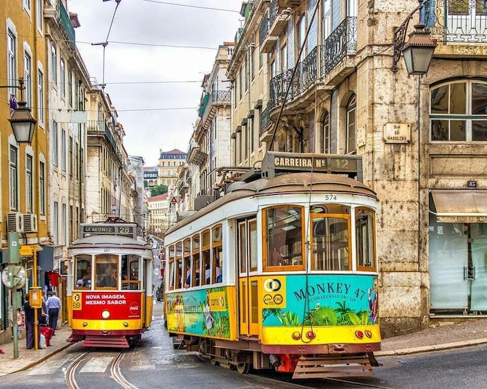 Two vintage trolleys on a narrow street, with buildings on either side. 5