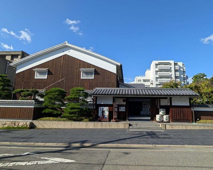 A traditional Japanese building with a wooden facade and a tiled roof, adjacent to a modern white building. 4