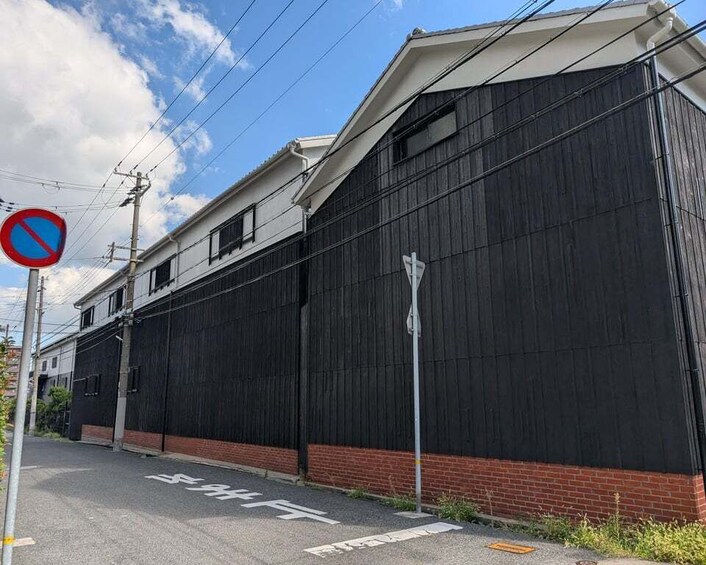A street with a no parking sign, a building with a black facade, and a clear blue sky. 2
