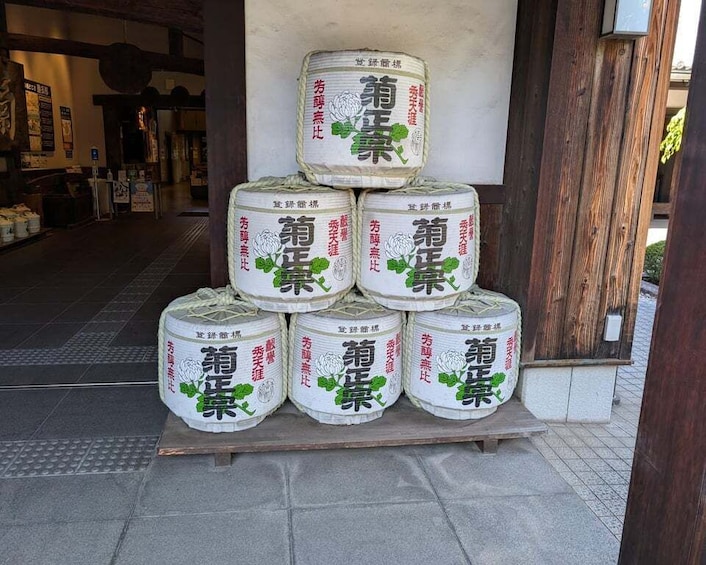 A stack of white containers with green text and images of a plant, placed outside a building with a wooden door. 1