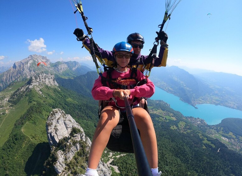 Two people paragliding over a mountainous landscape with a lake below. 4