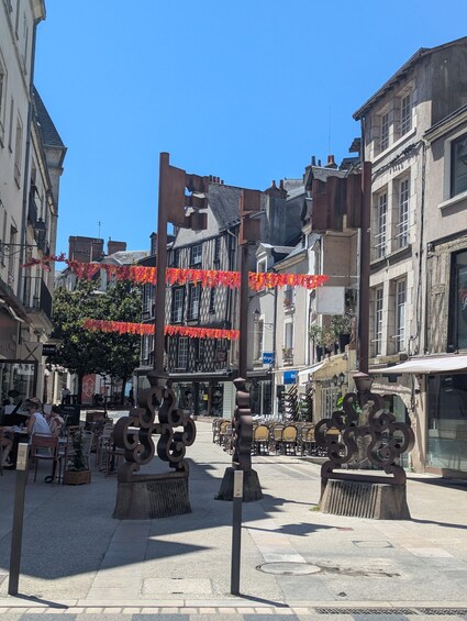 A street with buildings, outdoor seating, and decorative red garlands. 2