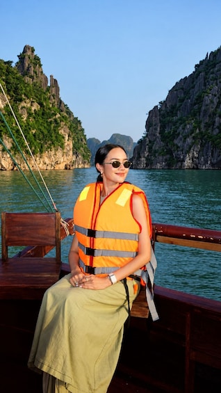 A person wearing a life jacket sitting on a boat with a mountainous landscape in the background. 3