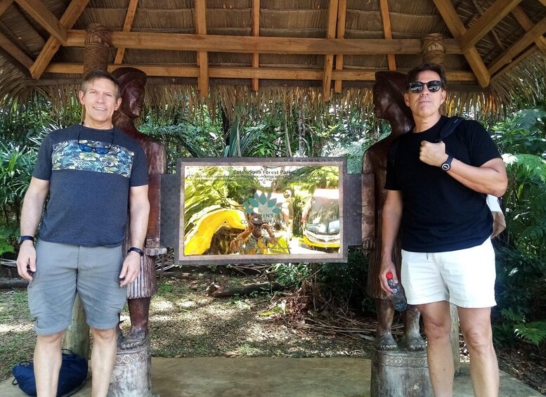 Two people standing in front of a wooden structure with a signboard. 5