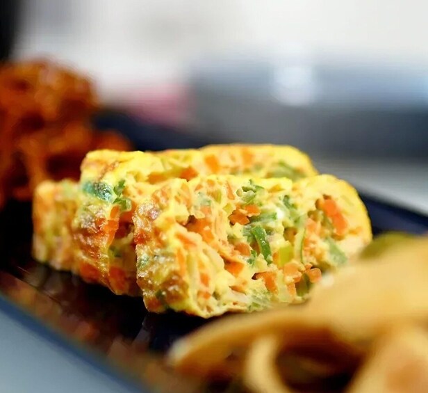 A close-up of a food item, possibly a savory omelette or frittata, with visible green and orange ingredients. 2