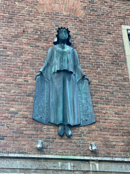 A statue of a woman with a halo on a brick wall. 5