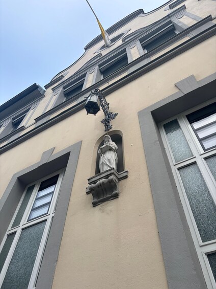 A building facade with a decorative window, a street lamp, and a statue. 4