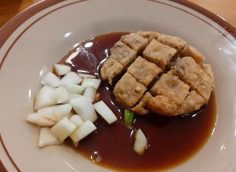 A plate with tofu, diced white radish, and a dark sauce. 4