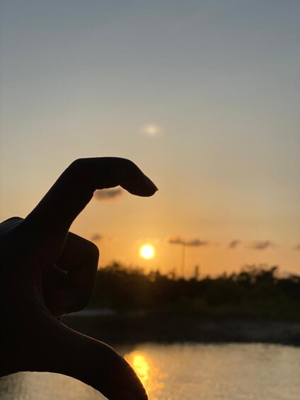A hand making a peace sign with the sun setting in the background. 1
