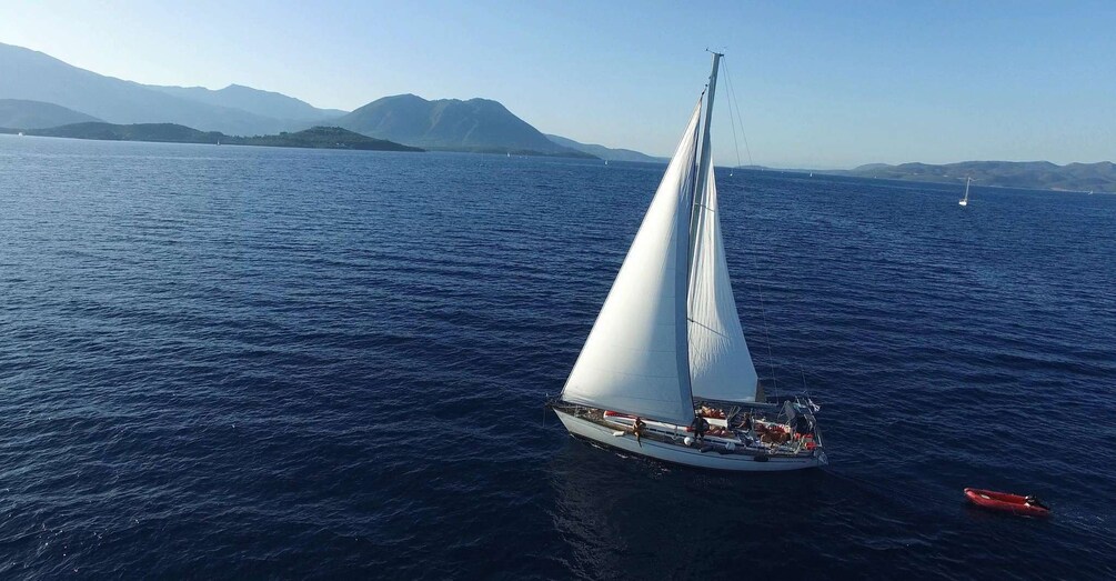 A sailboat on a calm sea with mountains in the background. 4