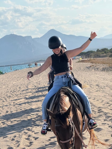 A person riding a horse on a beach with mountains in the background. 4