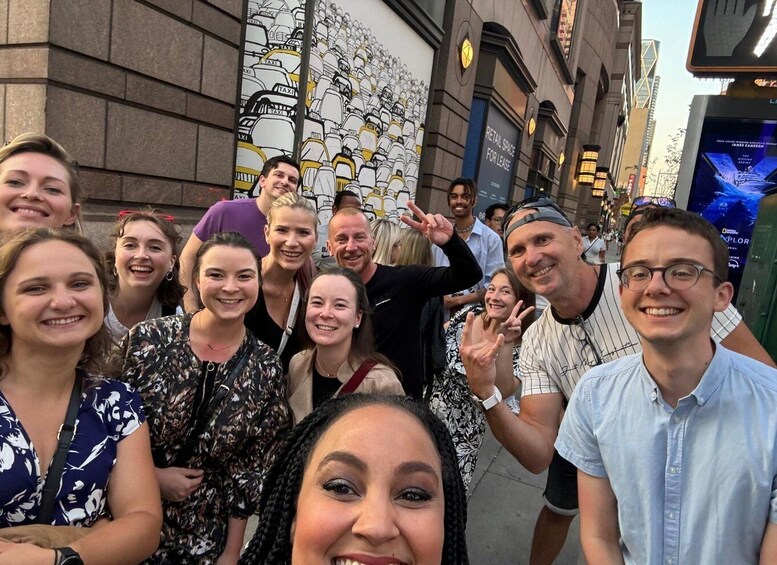A group of people posing in front of a building with a mural of taxis. 4