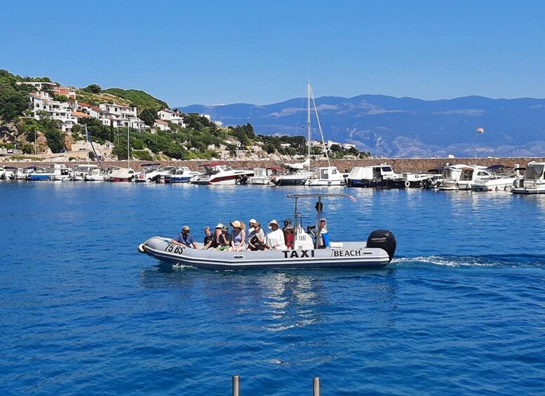 A boat with passengers labeled 'TAXI BEACH' on a calm body of water. 2