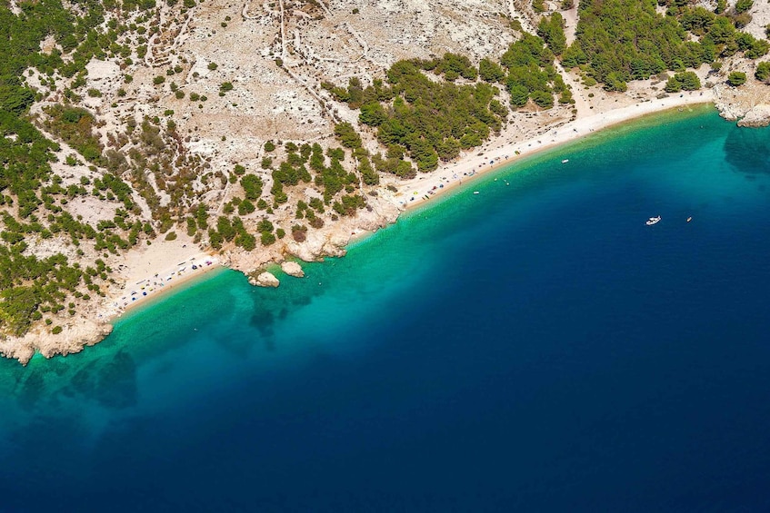 A coastal landscape with a sandy beach, clear turquoise waters, and scattered greenery. 5