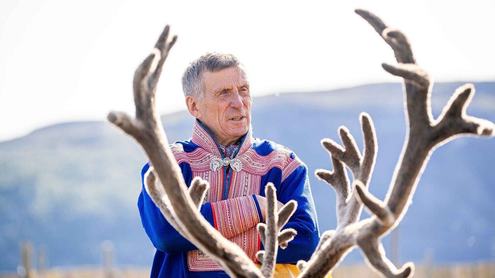 A person standing outdoors with a mountainous landscape in the background. 3