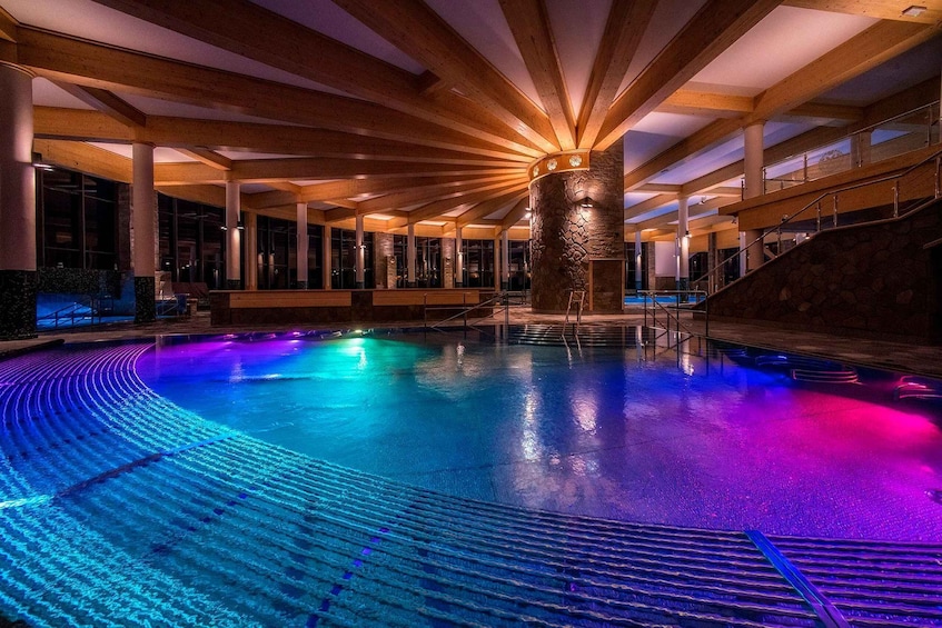 An indoor swimming pool with a central stone pillar and wooden beams. 2