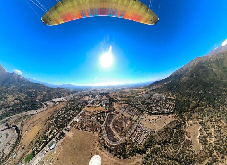 A paraglider over a mountainous landscape with a town below. 5