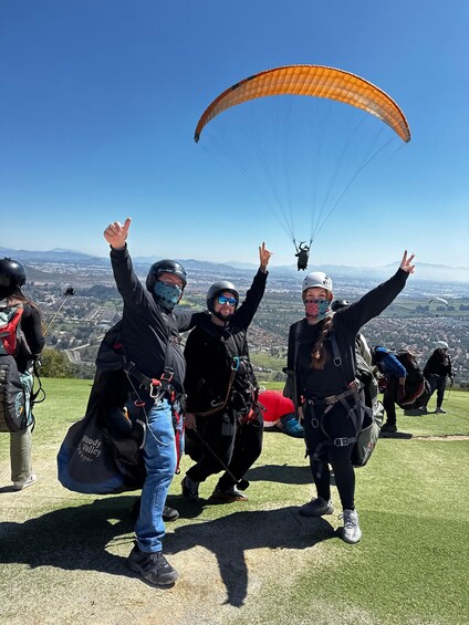 A group of people paragliding on a clear day with a cityscape in the background. 3