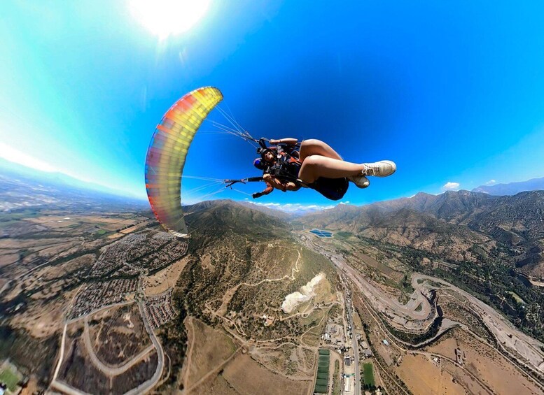A paraglider flying over a mountainous landscape with winding roads and a river. 4