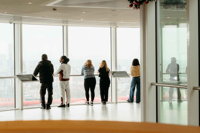 A group of people standing in a modern building with large windows overlooking a cityscape. 3