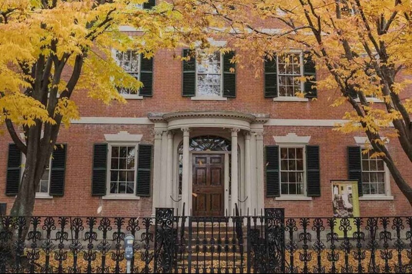 A brick building with green shutters and a central entrance with a decorative arch. 5