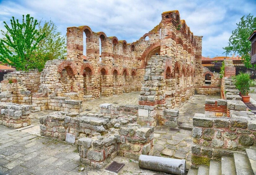 Ancient stone ruins with arches and walls, surrounded by greenery and a clear sky. 3
