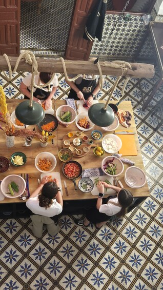 A group of people preparing food around a wooden table with various ingredients and utensils. 1