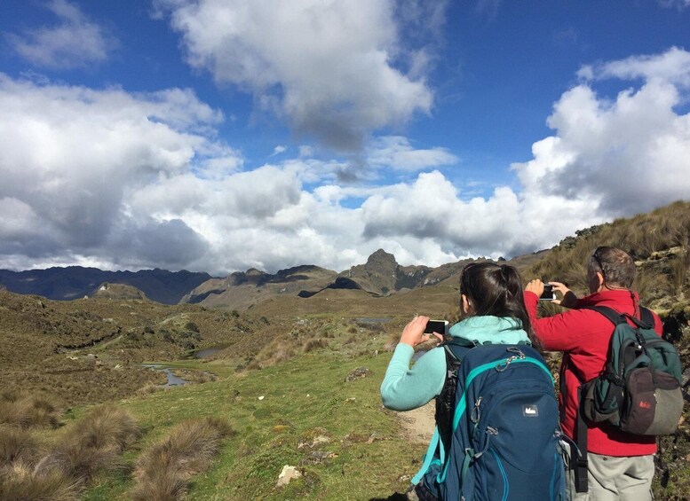 Zwei Wanderer mit Rucksäcken blicken auf eine gebirgige Landschaft mit einem See. 5