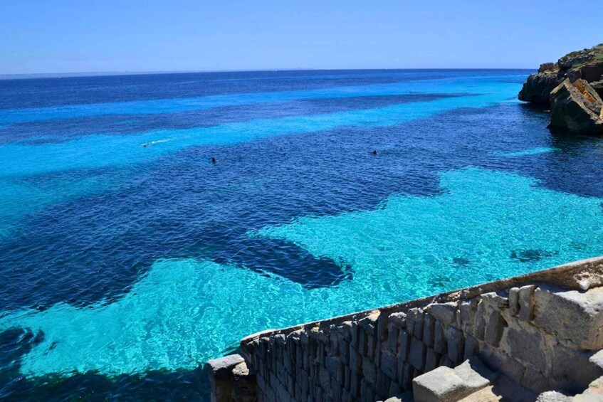 A coastal landscape with clear blue waters and rocky cliffs. 4