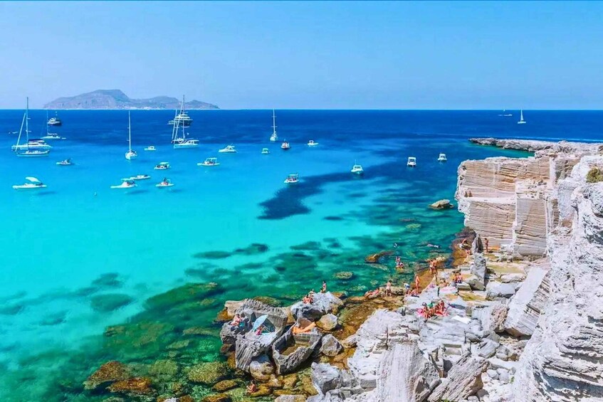 A coastal scene with boats on the water and rocky cliffs. 2