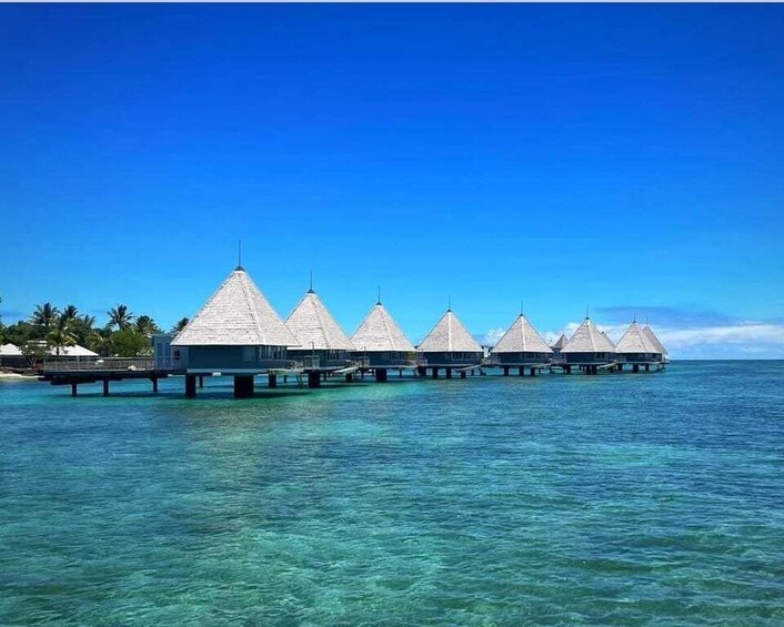 Overwater bungalows on stilts in clear turquoise water. 1