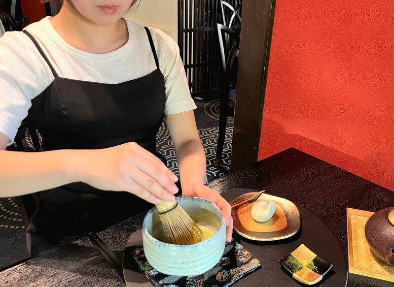 A person whisking a bowl of matcha tea. 1