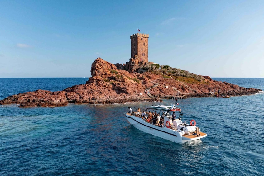 A rocky island with a tower and a boat with people on it. 1