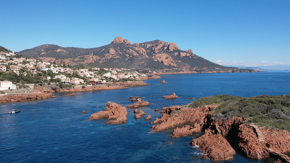 A coastal town with buildings, rocky outcrops, and a mountain in the background. 5