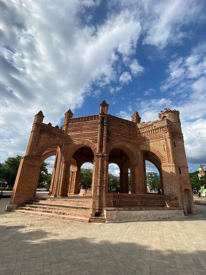 An ancient brick structure with arches and towers, set against a clear sky. 1