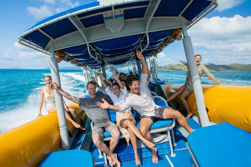 A group of people on a boat with a blue canopy, surrounded by water and distant land. 2