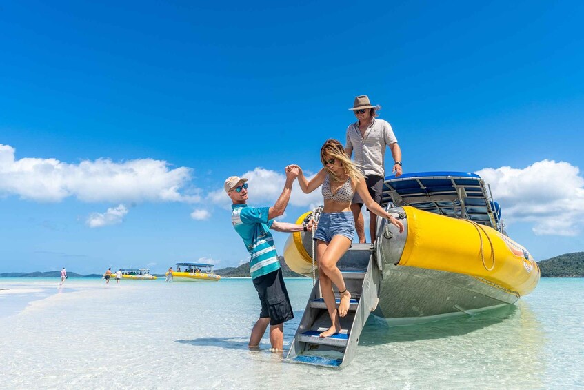 A group of people boarding a yellow inflatable boat on a beach. 4