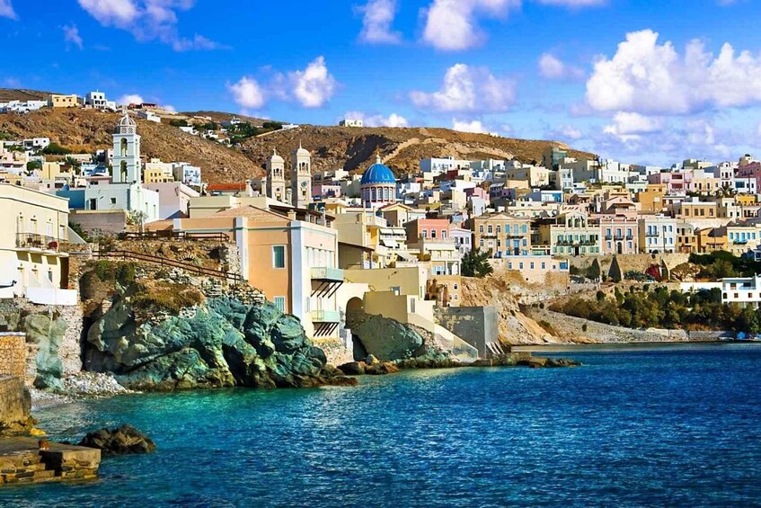 A coastal town with colorful buildings, a prominent church with a bell tower, and rocky cliffs. 1