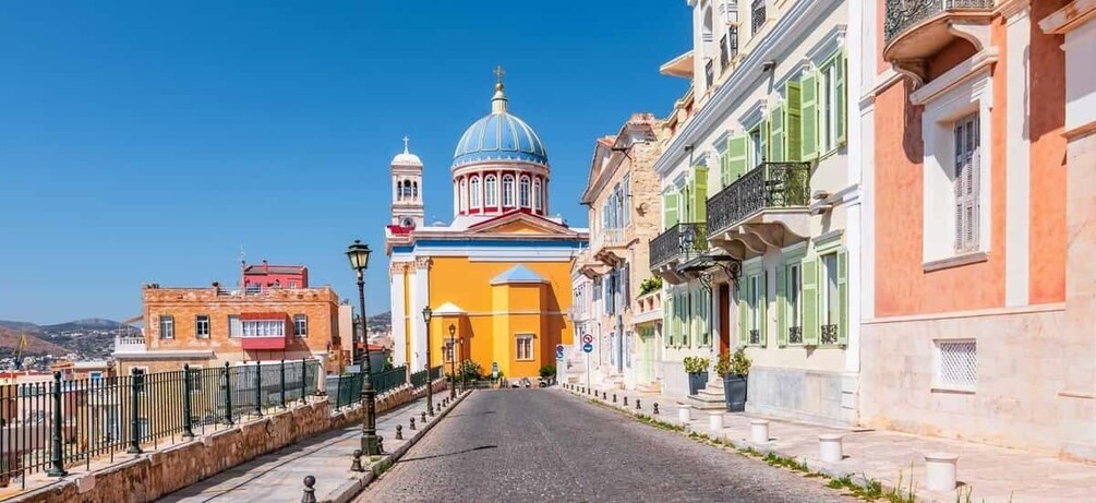 A street with colorful buildings, a prominent yellow church with a blue dome, and a clear blue sky. 3