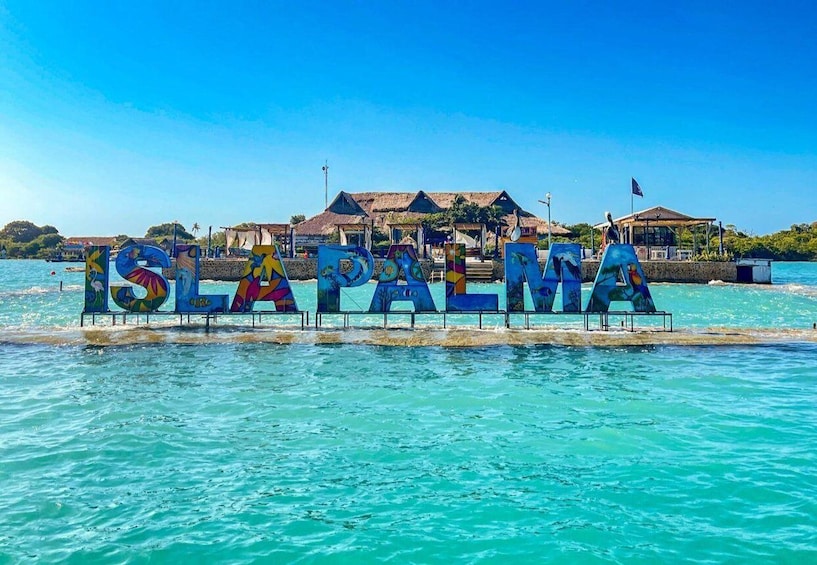 A sign spelling 'ISLA PALMA' in the water with buildings in the background. 5