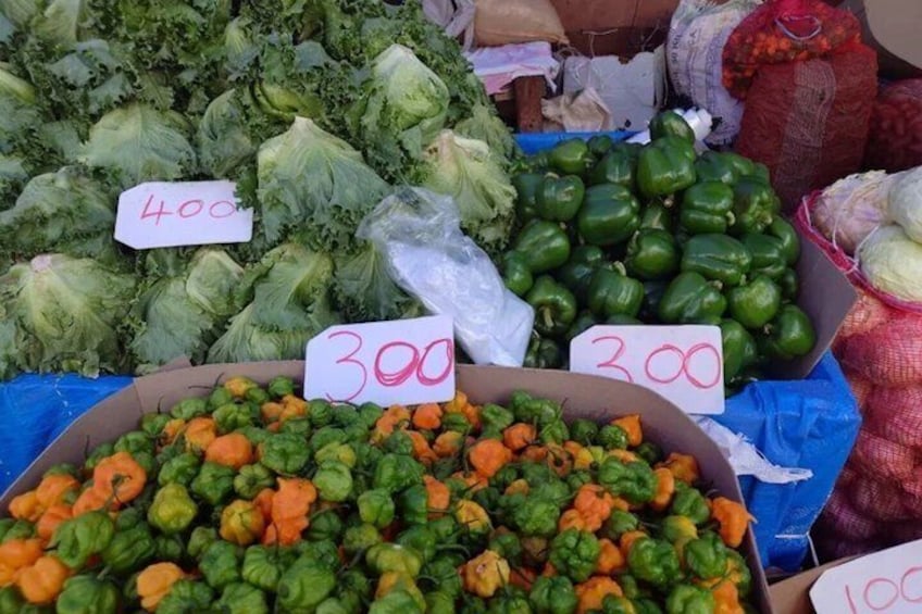 A market with various vegetables on display, including cabbages, green peppers, and carrots, with price tags. 2